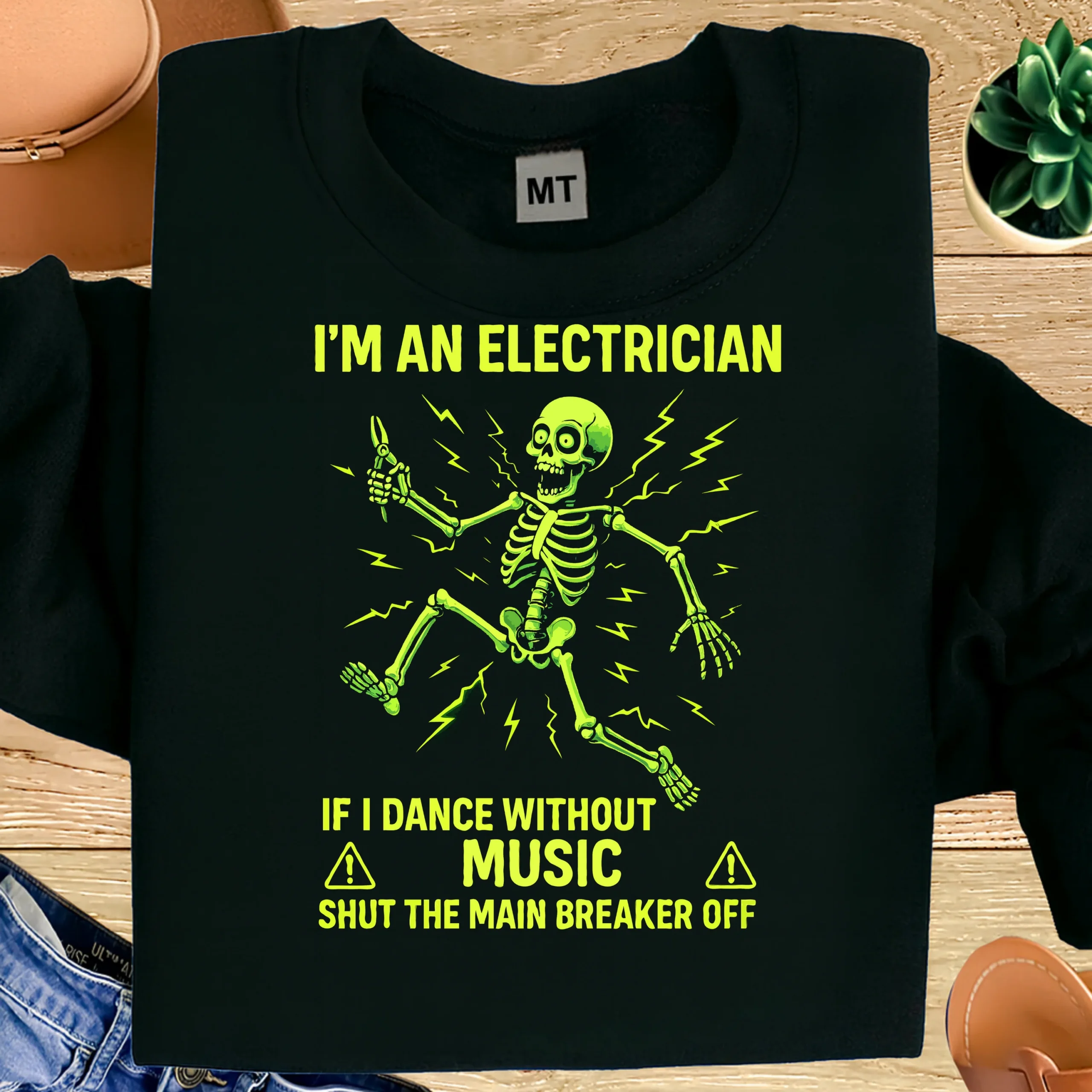 Funny electrician T-shirt with skeleton shock design. Premium cotton humor tee for electricians, linemen, and trade workers who love bold job-site jokes.